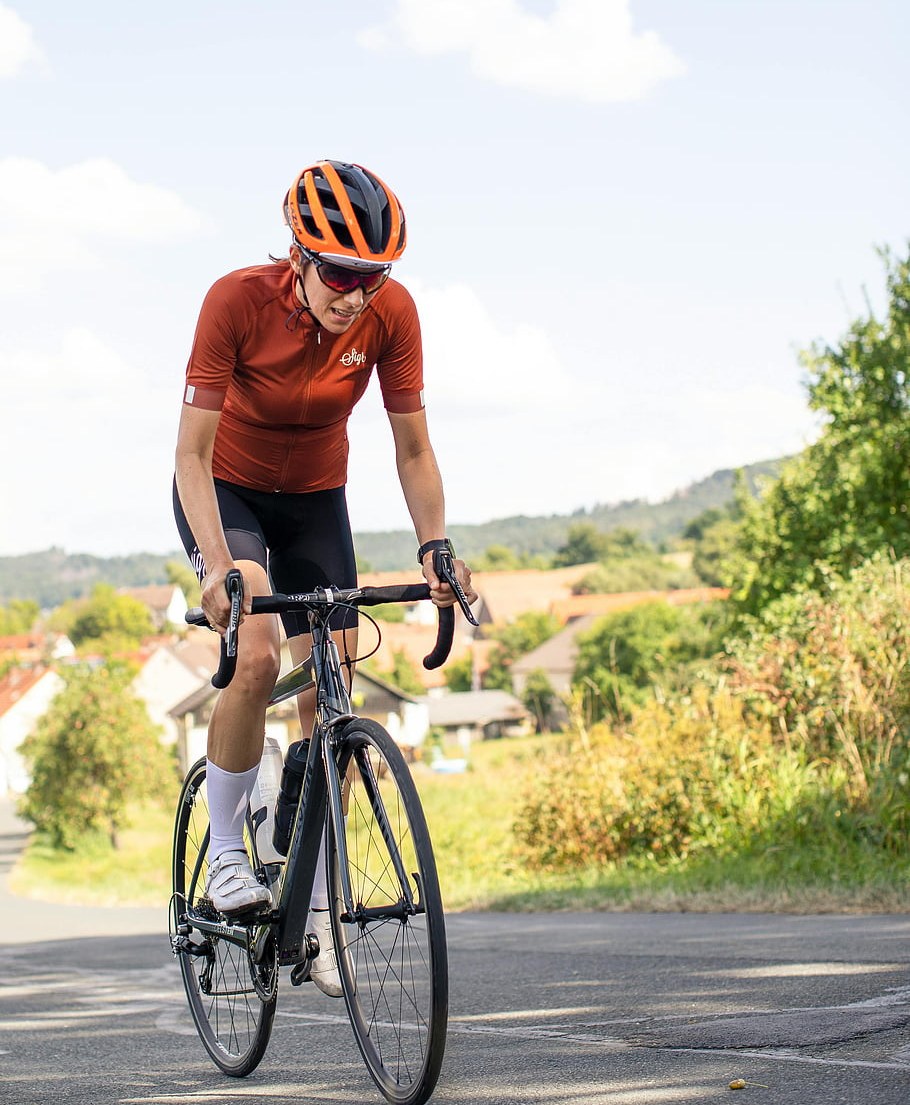 A triathlete standing on the pedals to climb a gentle hill on a quiet road
