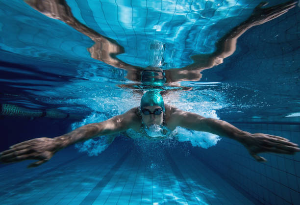 Underwater view of an adult swimmer exhaling steadily while swimming towards the camera