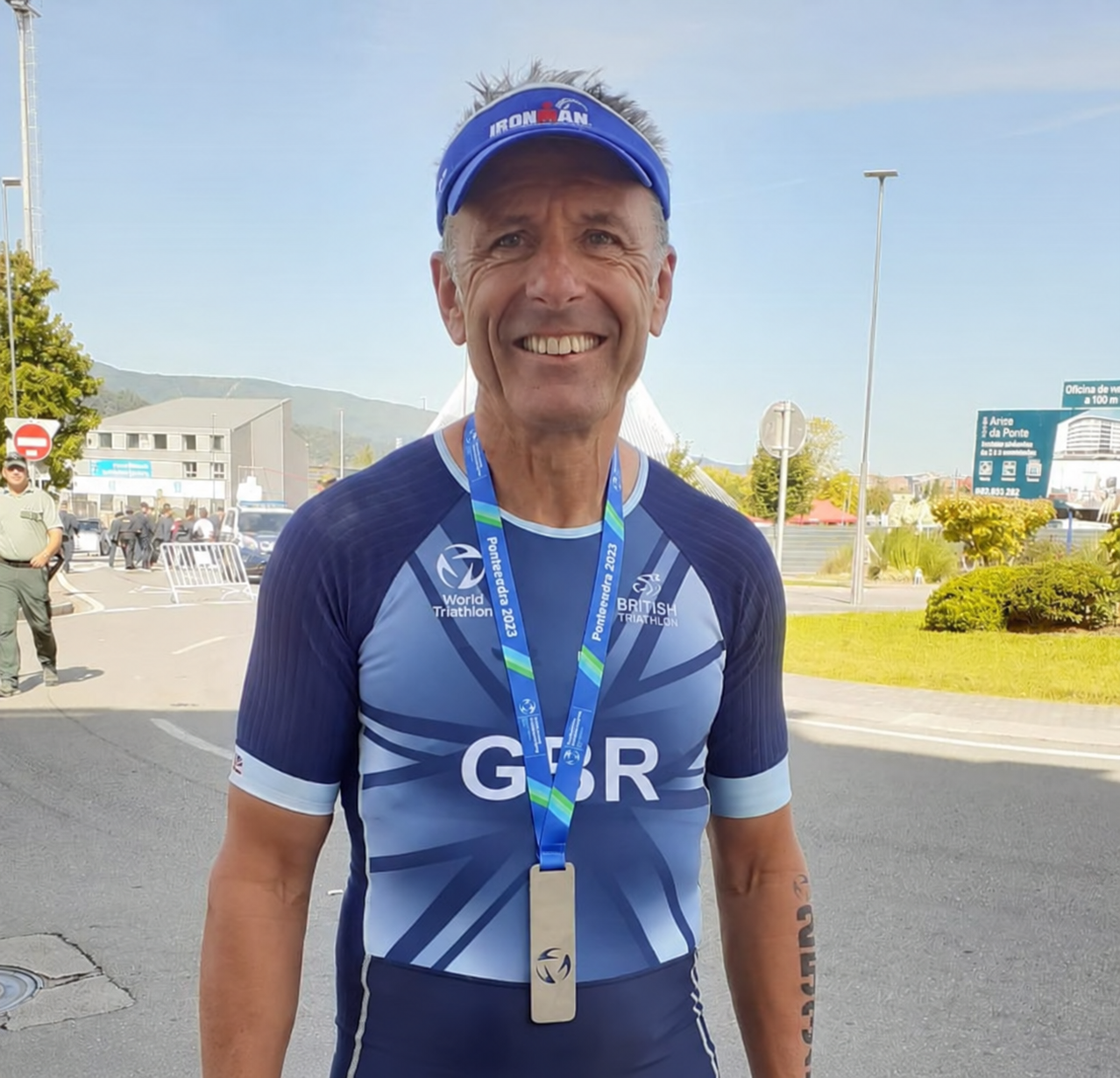 Triathlete wearing a Team GB race suit with an Ironman visor and finisher's medal after a race
