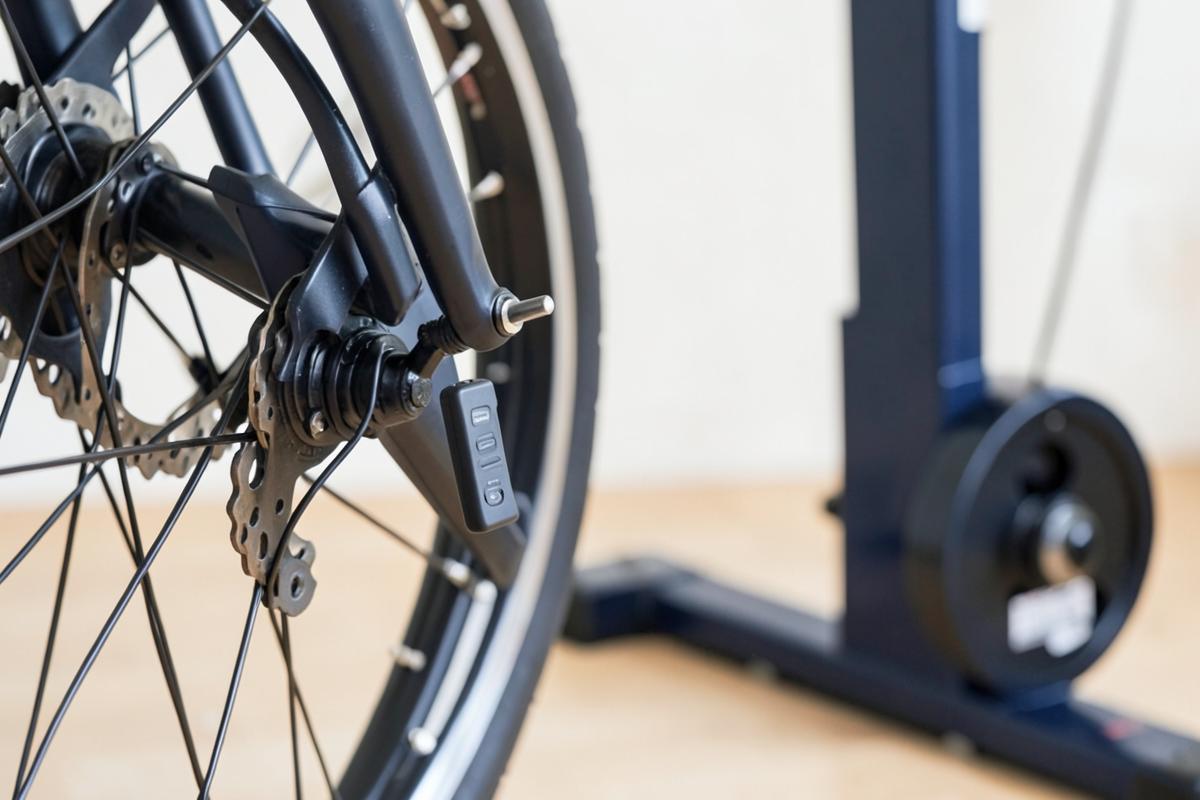 A small wireless speed sensor fitted to a rear wheel on a turbo trainer