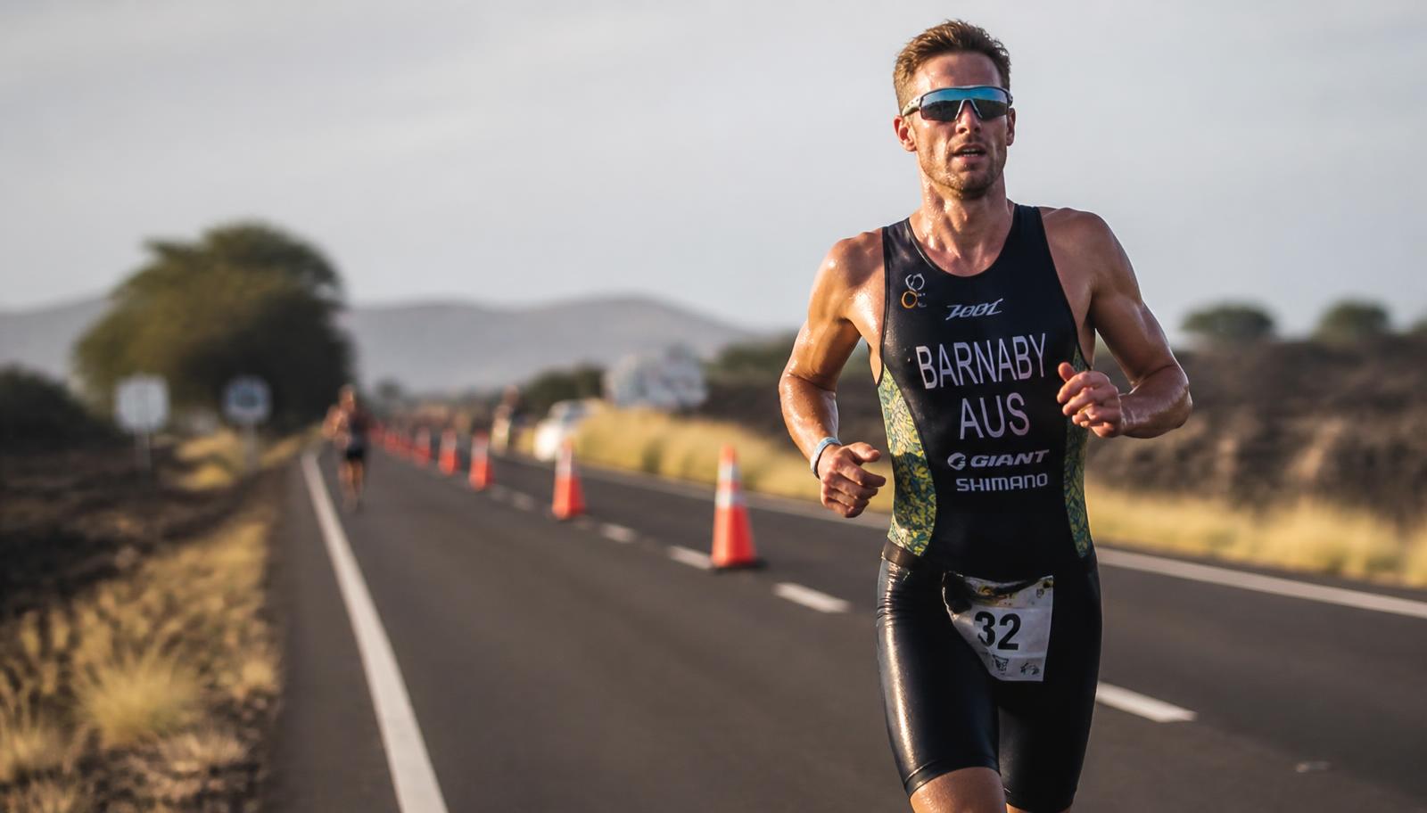 A triathlete running strongly on the final leg of a race in late afternoon light