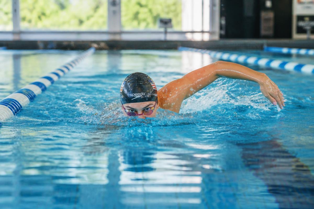 Swimmer practising front crawl in a pool lane with their eyes glancing forward towards the end of the lane